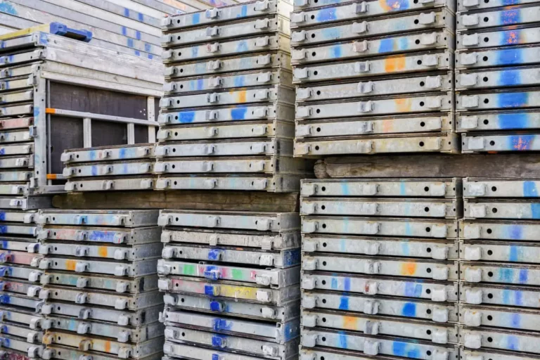 Stosy metalowych podestów i elementów tworzących rusztowanie używane na placu budowy.