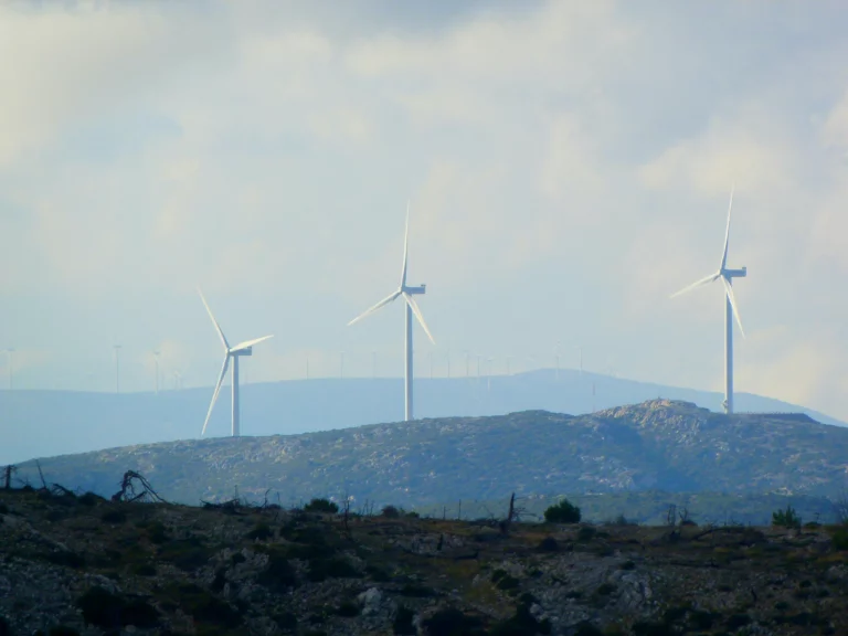Elektrownia wiatrowa na wzgórzach – symbol odnawialnych źródeł energii i działań zgodnych z zasadami ESG w budownictwie i gospodarce.